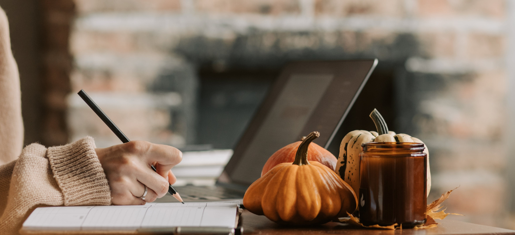 A professional copyeditor uses a pen to add suggestions to strengthen a piece of marketing copy. A laptop and a couple of pumpkins also sit on the desk.